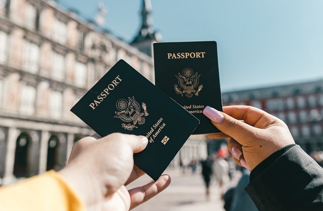 A interracial couple holding up their passports.